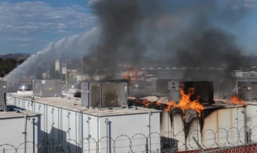een foto van een professioneel energie opslag systeem in tientallen containers waarbij één van die containers in de brand staat vanwege een thermal runaway