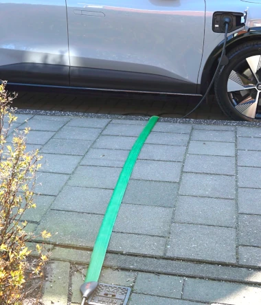 foto van een platte laadkabel voor een ev die op de stoep ligt