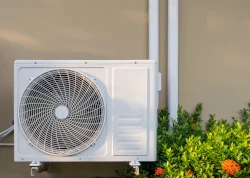 lucht/lucht warmtepomp buitenunit die aan de buitenmuur hangt vlak boven de grond