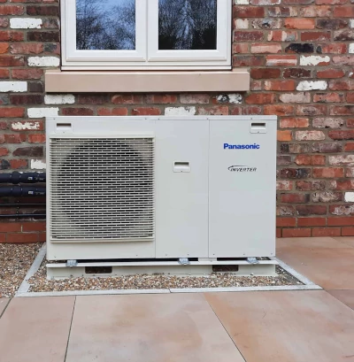 warmtepomp buitenunit van panasonic geplaatst tegen de gevel onder het raam